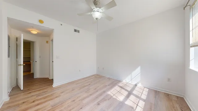 a view of empty room with wooden floor and fan