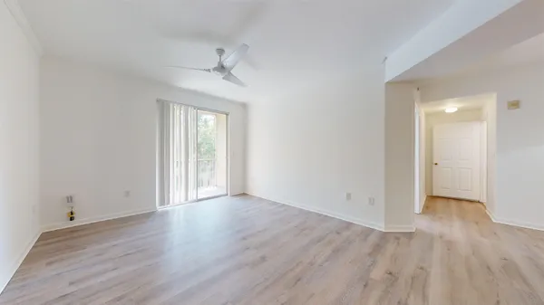 a view of an empty room with wooden floor and a window