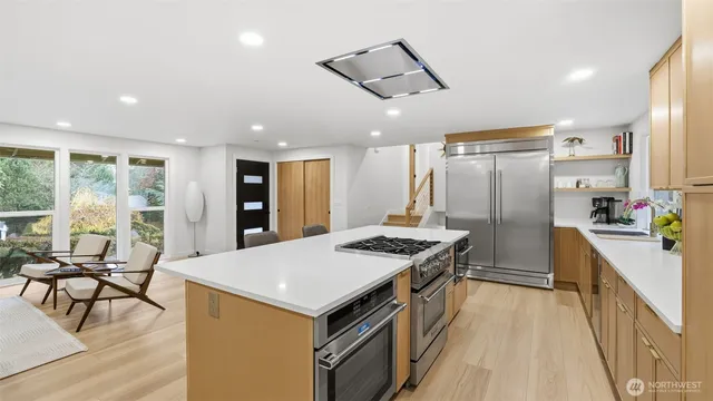 a kitchen with kitchen island a large counter top space a sink stainless steel appliances and cabinets