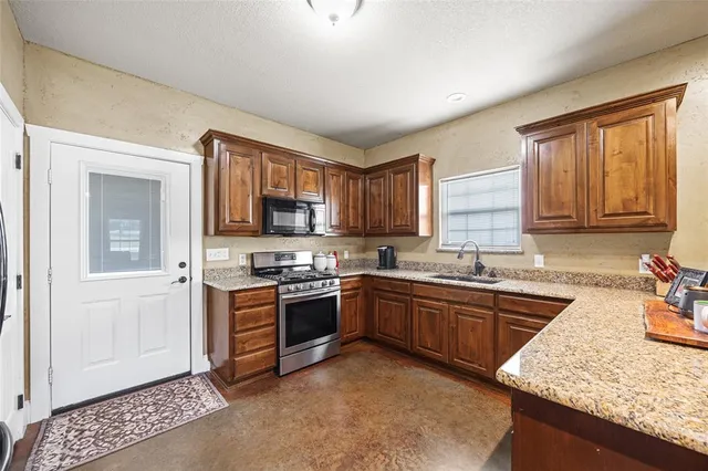 a kitchen with stainless steel appliances granite countertop wooden cabinets a sink and a stove