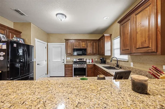 a kitchen with stainless steel appliances granite countertop a stove top oven a sink dishwasher a dining table and chairs with wooden floor