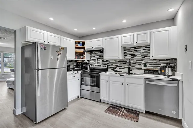 a kitchen with white cabinets and stainless steel appliances