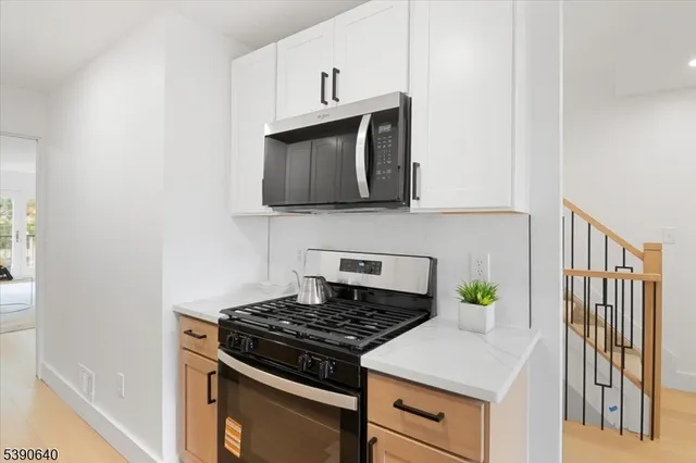 a kitchen with granite countertop stainless steel appliances a stove top oven a sink and white cabinets