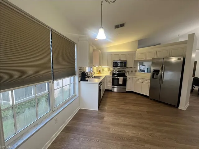 a kitchen with stainless steel appliances kitchen island granite countertop a refrigerator a stove and a wooden floors