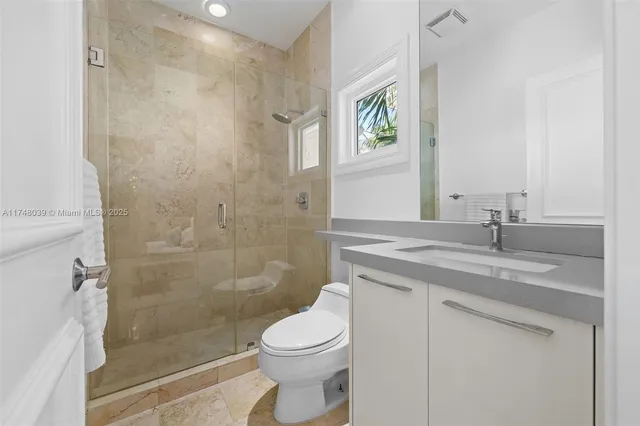 a bathroom with a granite countertop sink a toilet and shower