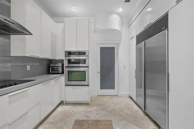 a kitchen with stainless steel appliances kitchen island granite countertop a refrigerator and a stove top oven