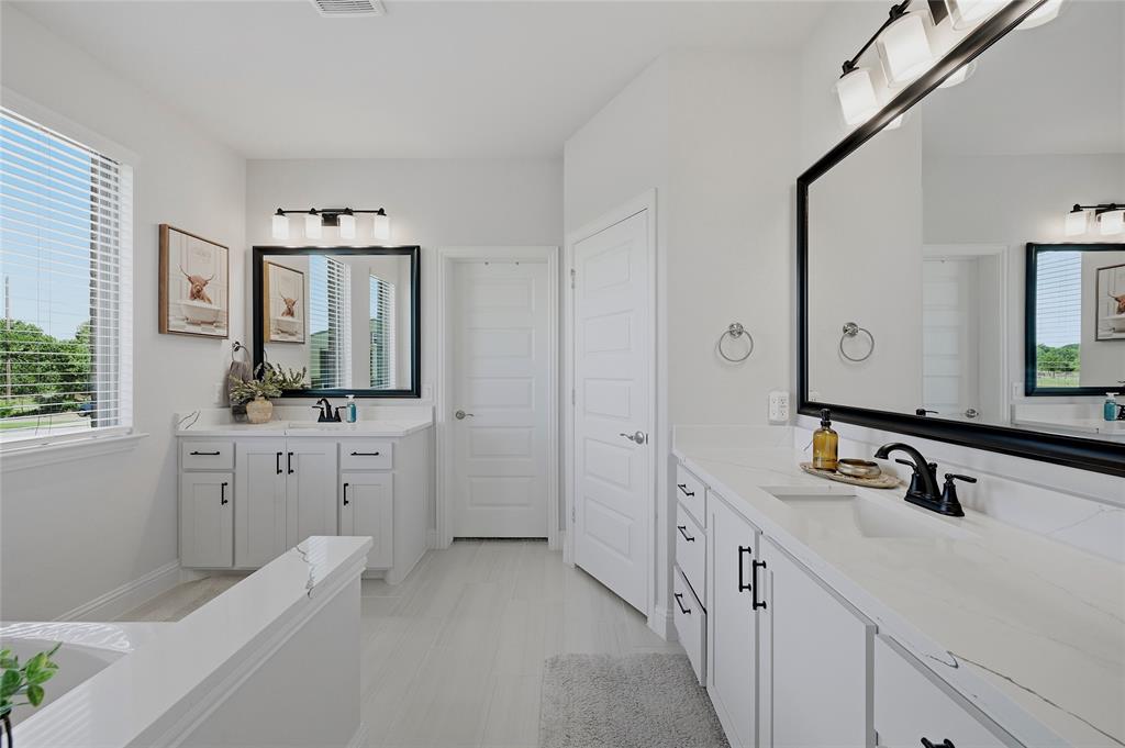 864 Shadow Valley Road Whitesboro, TX 76273 - Photo 23 of 40 Spacious bathroom featuring dual vanities with white cabinetry, quartz countertops, and matte black fixtures