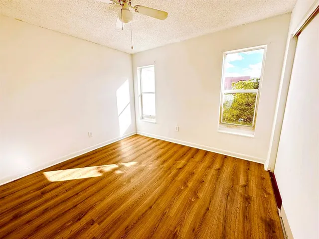 a view of empty room with wooden floor and fan