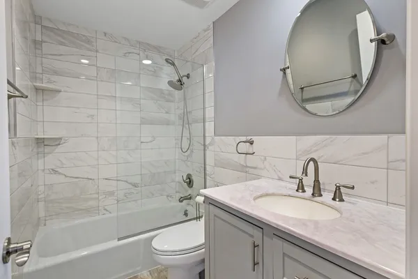 a bathroom with a granite countertop sink a toilet and shower