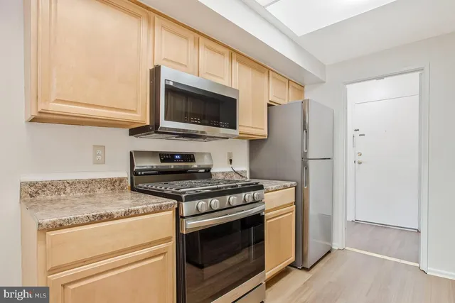 a kitchen with stainless steel appliances granite countertop a sink a stove a refrigerator and island with wooden floor