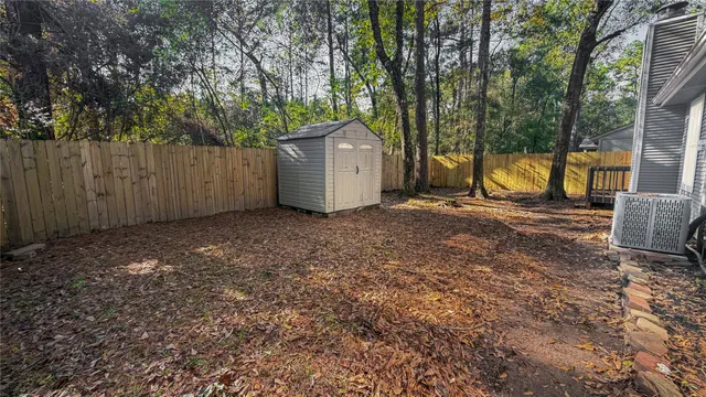 a view of a backyard with large tree and wooden fence