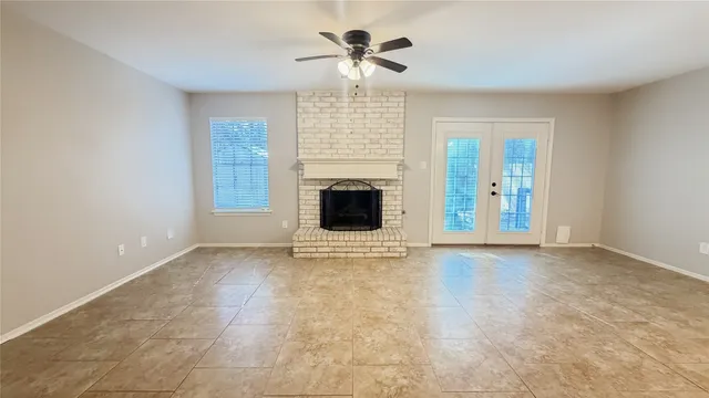 a view of an empty room with chandelier fan and fire place