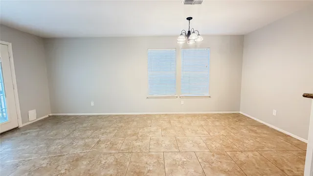 an empty room with chandelier fan and windows