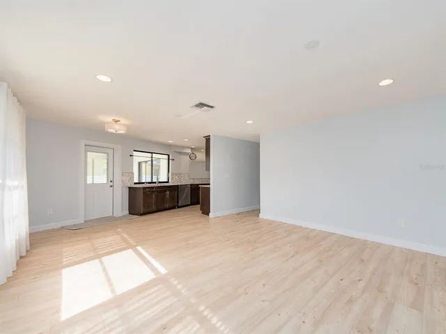 a view of an empty room with window and wooden floor