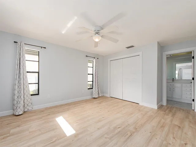 a view of empty room with wooden floor and fan