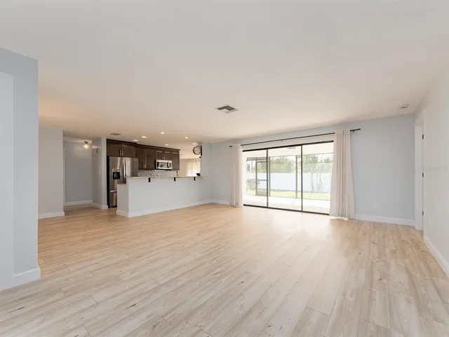 a view of empty room with wooden floor and window