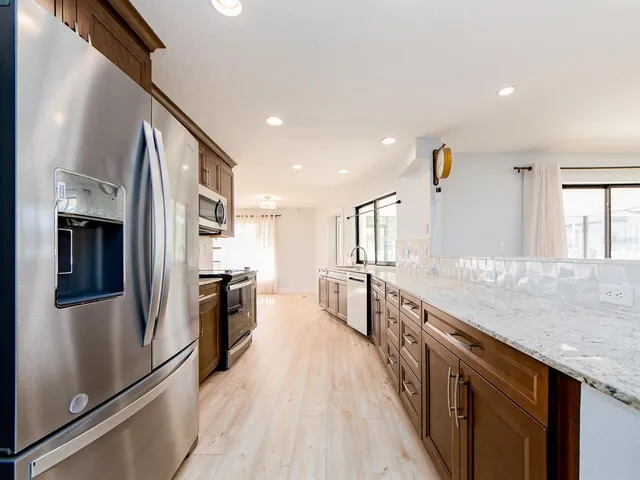 a kitchen with stainless steel appliances granite countertop a refrigerator a stove and a sink