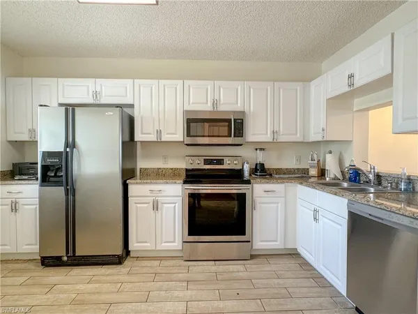 a kitchen with cabinets stainless steel appliances and a window