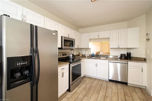 a kitchen with stainless steel appliances a refrigerator a stove a sink cabinets and a wooden floor