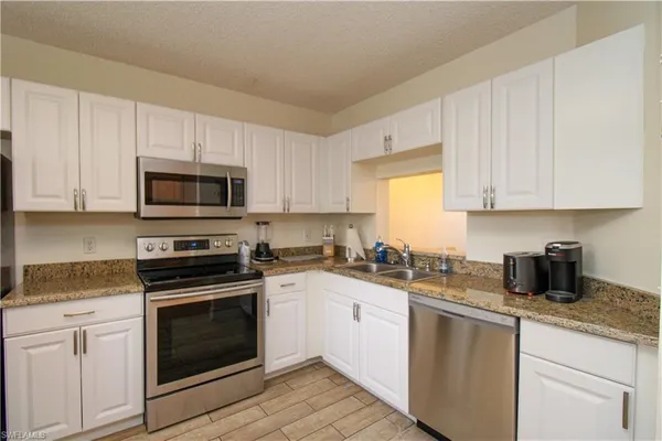 a kitchen with sink a microwave and cabinets