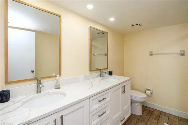 a bathroom with a granite countertop sink a toilet and a mirror