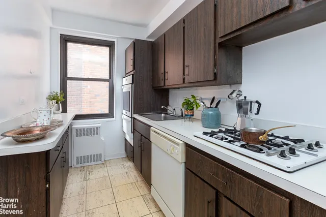 a kitchen with a sink a stove cabinets and a window