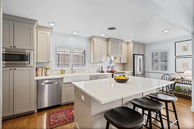 a kitchen with a sink a stove and chairs with wooden floor
