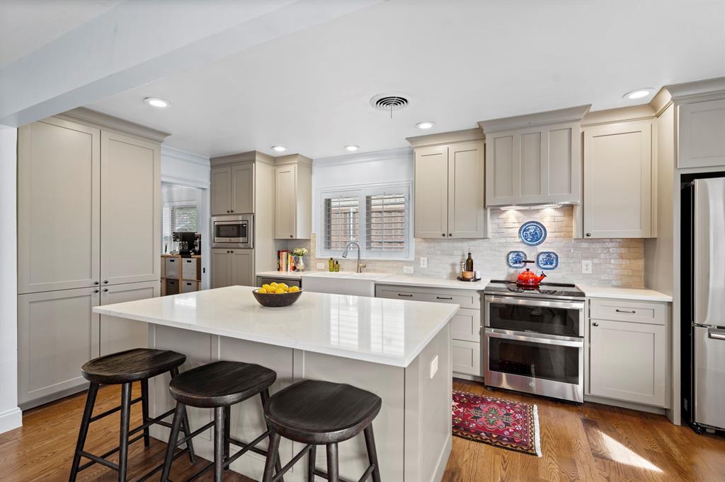 5322 Ridgelawn Drive Dallas, TX 75214 - Photo 10 of 30 a kitchen with a sink a stove and chairs with wooden floor