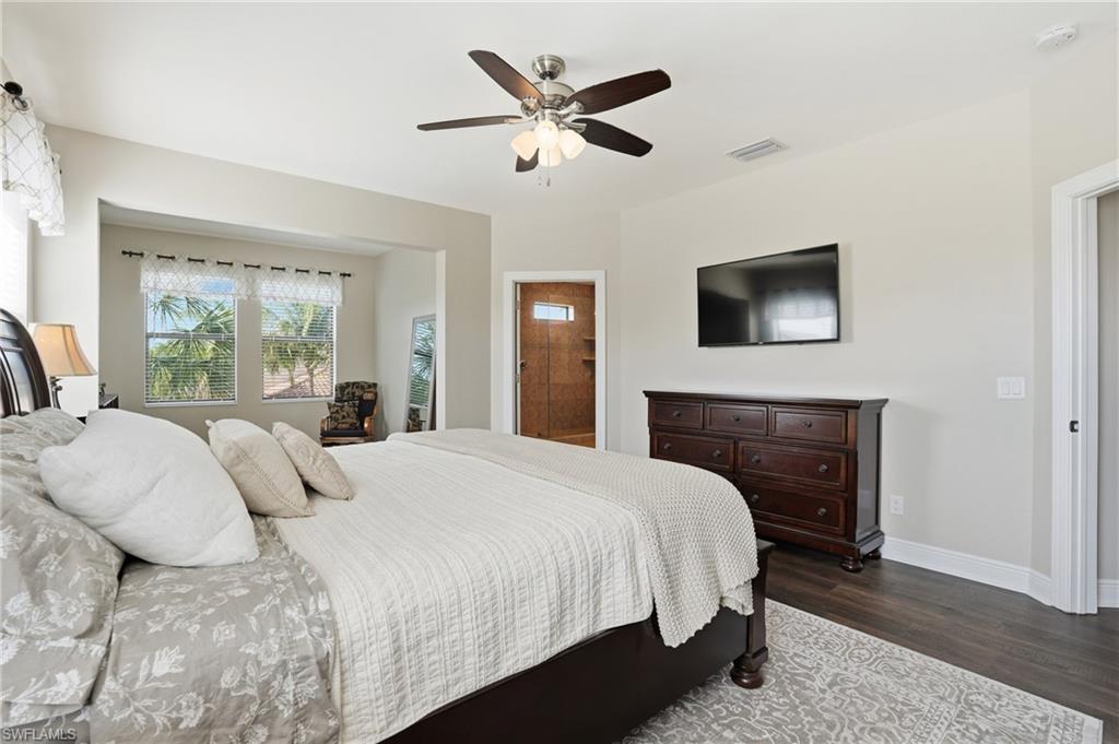 4609 Abaca Circle Naples, FL 34119 - Photo 21 of 49 a bedroom with a large bed a chandelier and a flat screen tv