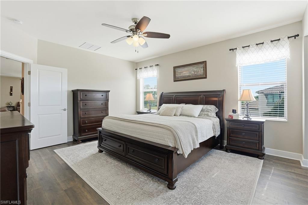 4609 Abaca Circle Naples, FL 34119 - Photo 22 of 49 a spacious bedroom with a bed a dresser and a chandelier