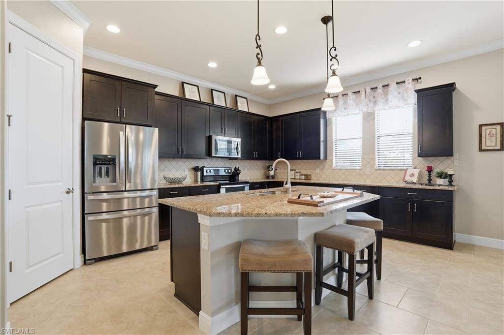 4609 Abaca Circle Naples, FL 34119 - Photo 8 of 49 a kitchen with kitchen island a sink stove a refrigerator and a oven with wooden floor