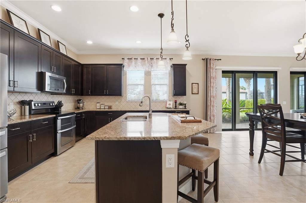 4609 Abaca Circle Naples, FL 34119 - Photo 9 of 49 a kitchen with stainless steel appliances granite countertop a sink counter space and cabinets