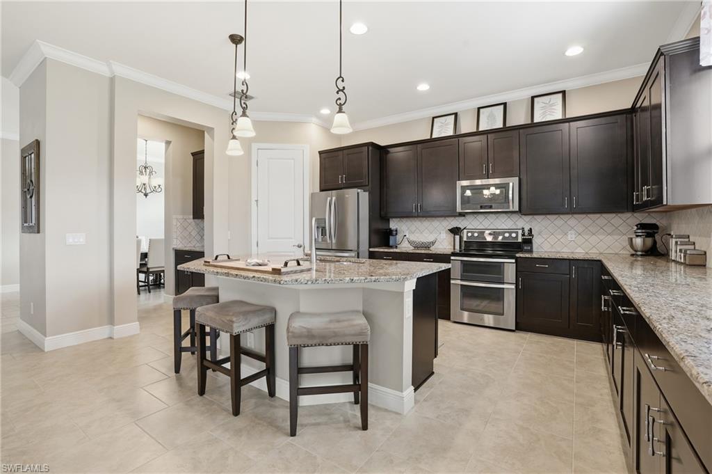 4609 Abaca Circle Naples, FL 34119 - Photo 10 of 49 a kitchen with kitchen island granite countertop a sink a counter top space appliances and cabinets