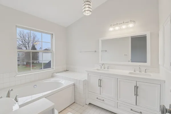 a bathroom with a tub sink and mirror