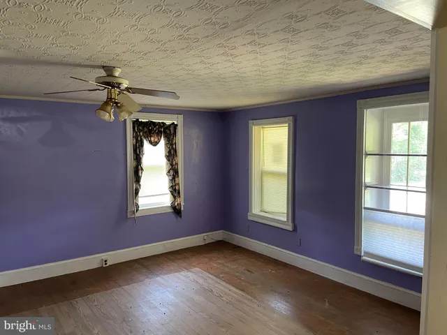 an empty room with windows and chandelier fan