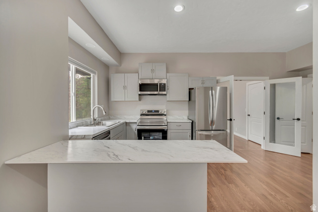 2154 Wasatch Boulevard Sandy, UT 84092 - Photo 48 of 55 Kitchen with stainless steel appliances, a peninsula, light wood-style flooring, recessed lighting, and light stone counters