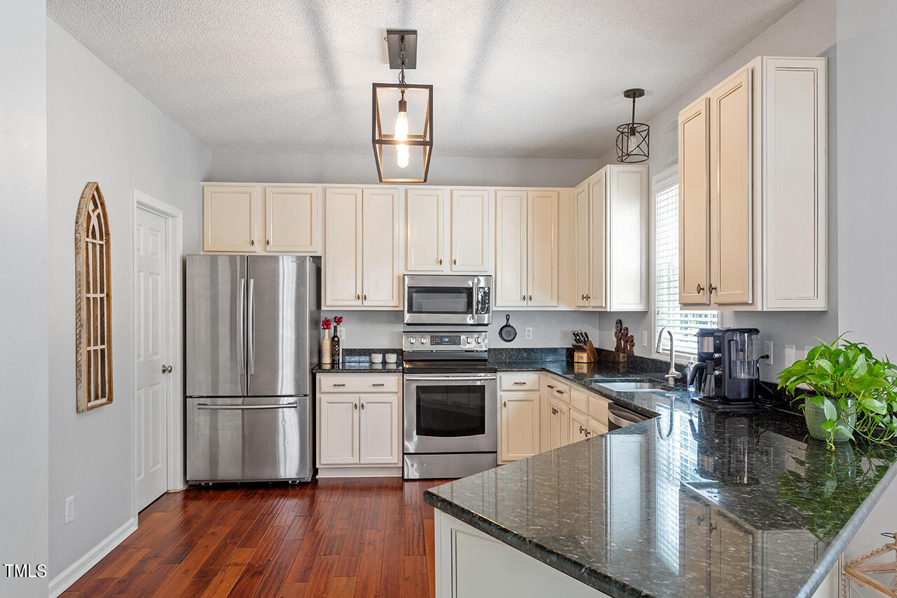 689 Seastone Street Raleigh, NC 27603 - Photo 5 of 34 a kitchen with stainless steel appliances granite countertop a refrigerator a stove a sink cabinets and a wooden floor