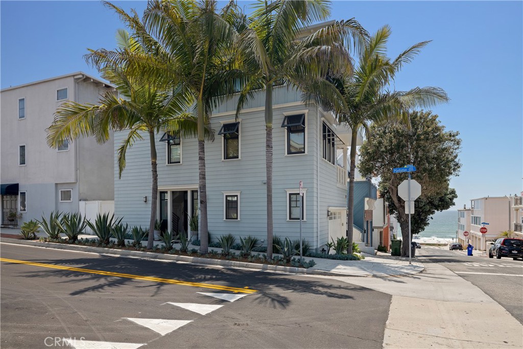 a front view of a house with a yard and palm trees