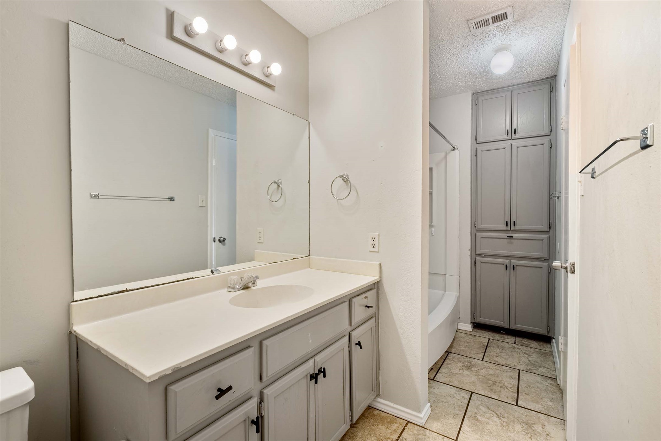 3904 Hudson Bend Road, Unit A Austin, TX 78734 - Photo 13 of 23 Bathroom featuring vanity, shower / bathtub combination, a textured ceiling, and light tile patterned flooring