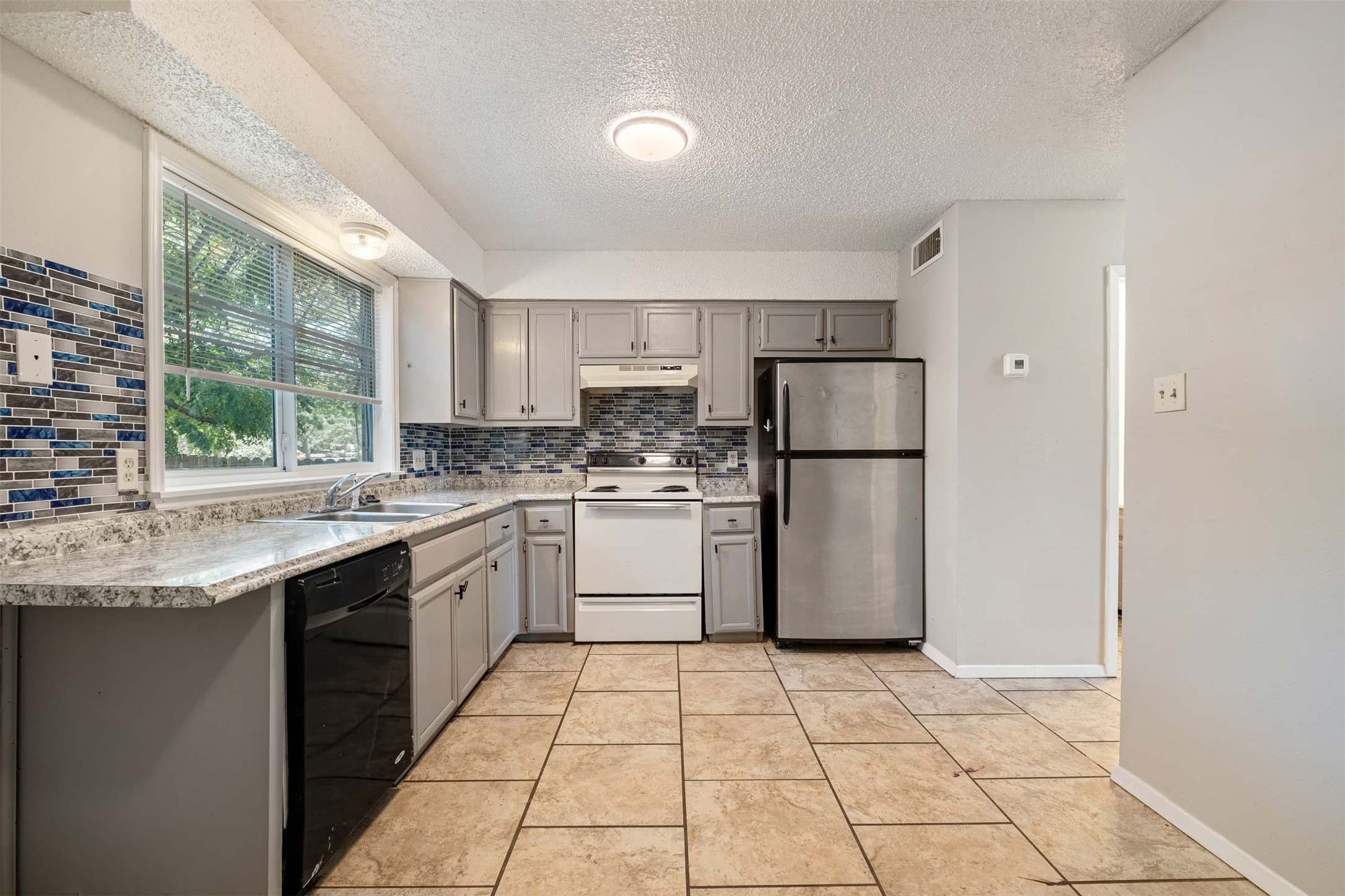 3904 Hudson Bend Road, Unit A Austin, TX 78734 - Photo 6 of 23 Kitchen featuring gray cabinets, light countertops, freestanding refrigerator, white electric range, and dishwasher