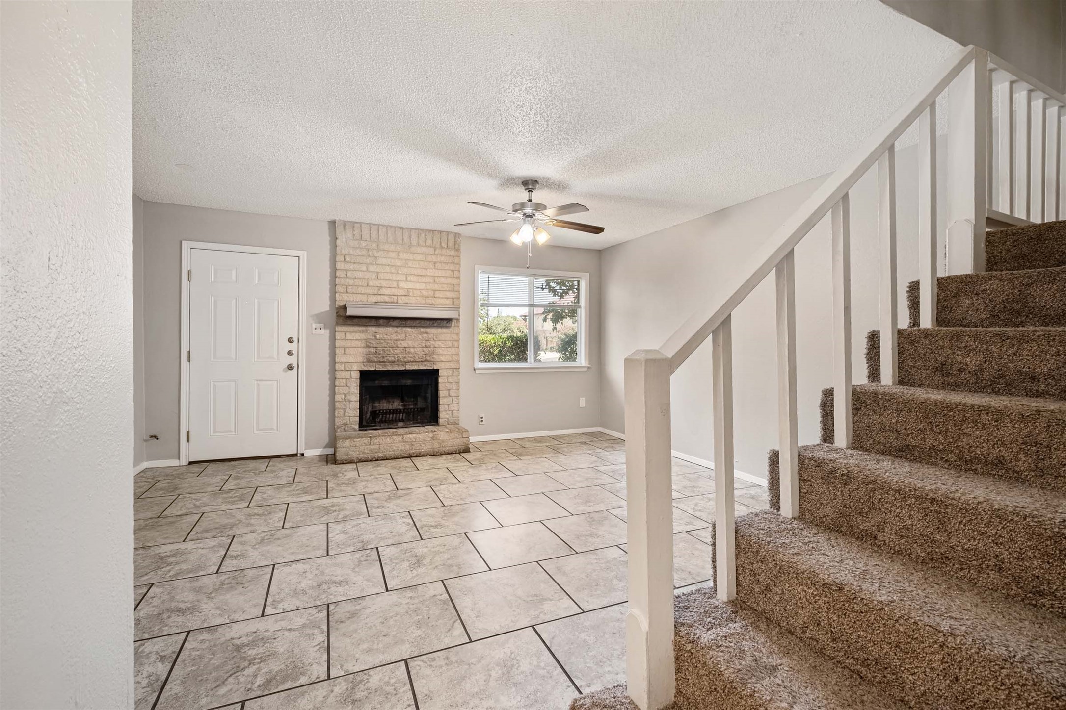 3904 Hudson Bend Road, Unit A Austin, TX 78734 - Photo 7 of 23 Unfurnished living room with a textured ceiling, ceiling fan, a fireplace, and light tile patterned flooring