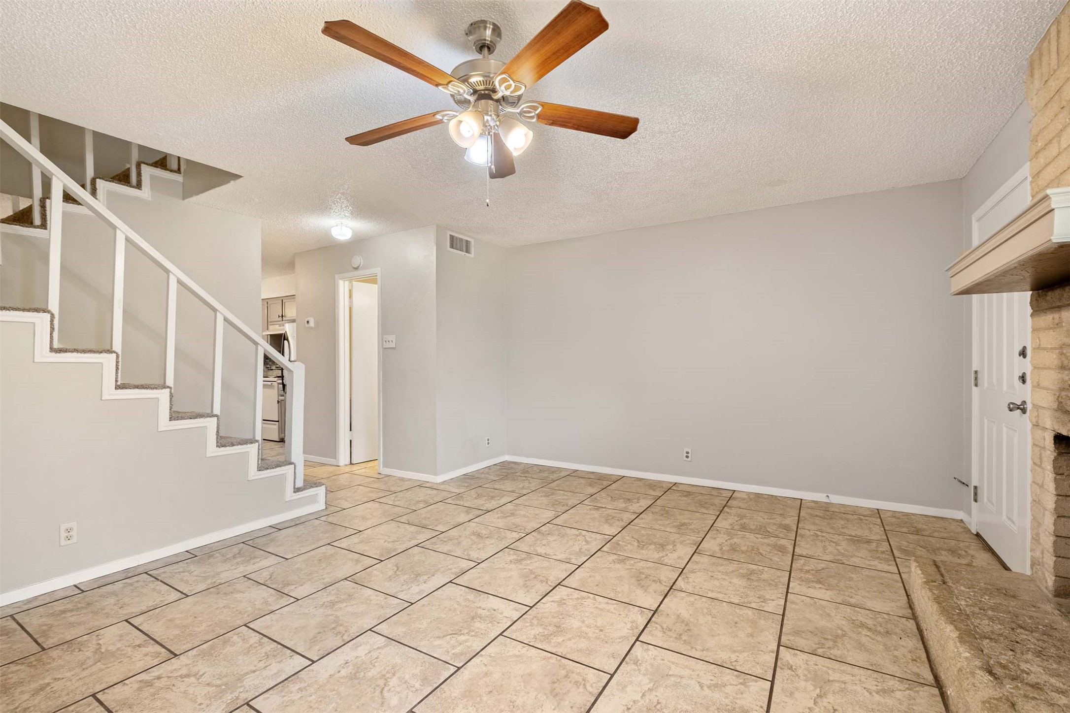 3904 Hudson Bend Road, Unit A Austin, TX 78734 - Photo 9 of 23 Unfurnished living room with a ceiling fan, a textured ceiling, a brick fireplace, and light tile patterned floors