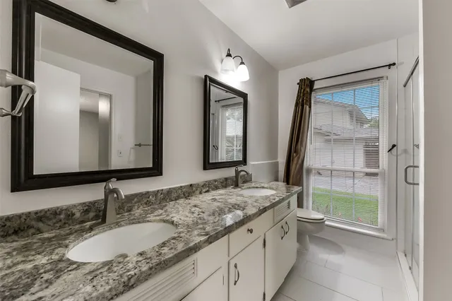 a bathroom with a granite countertop double vanity sink and a mirror
