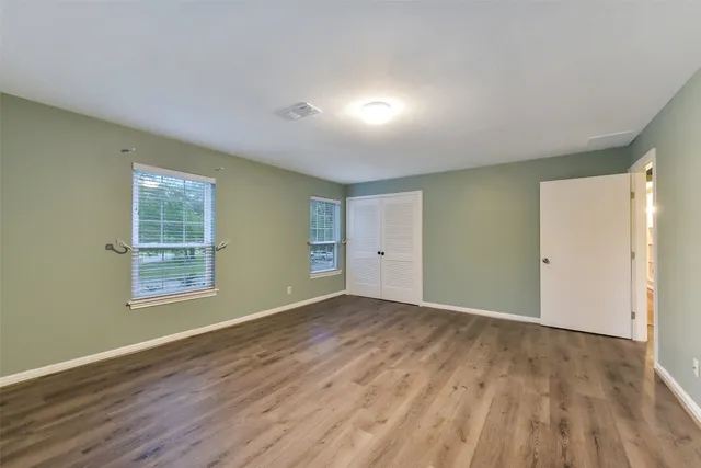 an empty room with wooden floor and windows