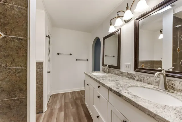 a bathroom with a granite countertop double vanity sink and a mirror