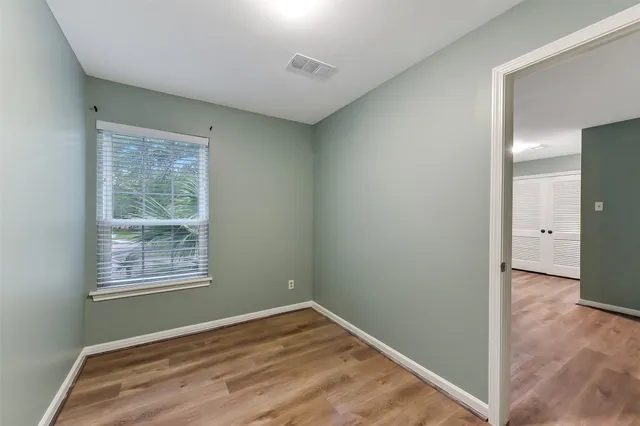 a view of an empty room with wooden floor and a window