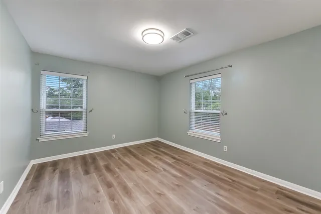 a view of an empty room with a window and wooden floor