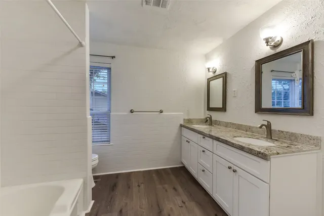 a bathroom with a granite countertop sink a mirror and a bathtub