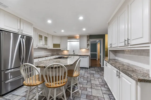 a kitchen with granite countertop a stove a sink and a refrigerator