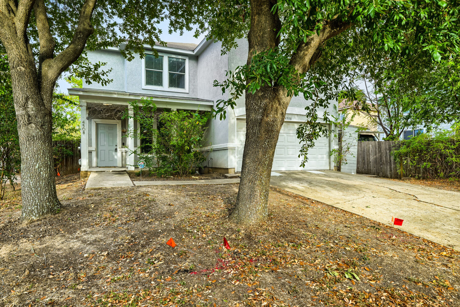 4508 Peach Grove Road Austin, TX 78744 - Photo 21 of 22 Mature trees frame the facade of this two-story home featuring an attached two-car garage.